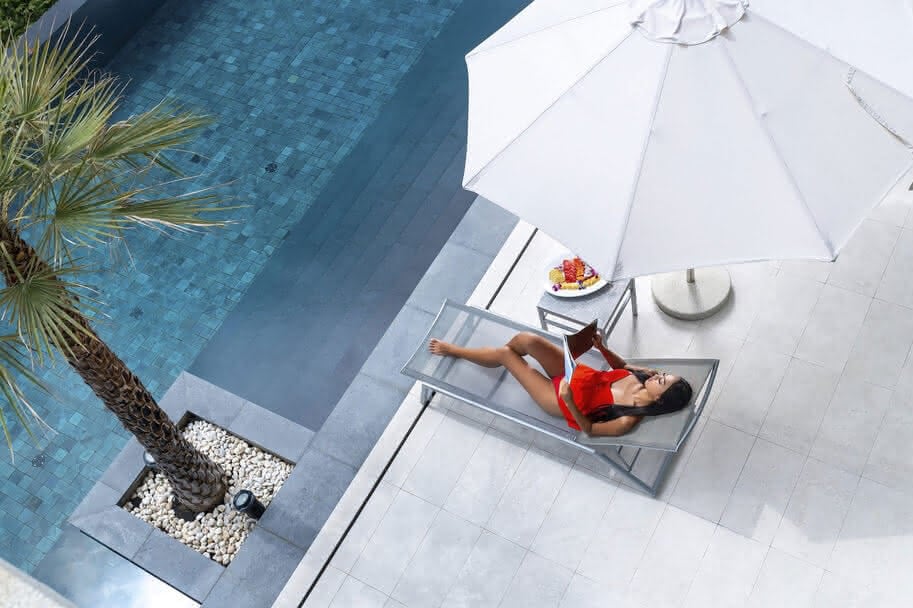 Guest reading on a sunbed beside a hotel pool